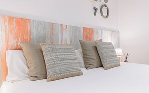 Een bed met meerdere kussens, een witte muur en decoratief het getal '70' op de muur.