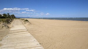 Une vaste plage de sable bordée d’une promenade en bois qui mène à l’eau.