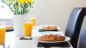 Ett frukostbord med ett ur, blommor och croissanter.