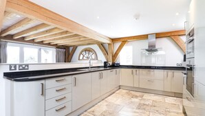 A modern kitchen with white cabinets, a black countertop, and a large island. - Beach Side -  a house that sleeps 8 guests  in 4 bedrooms (Bembridge)