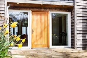 A wooden door with a glass panel, a stone-paved entrance, and a wooden exterior wall.