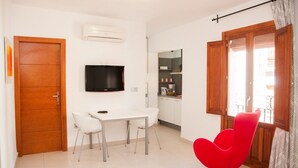 A compact living space with a dining area, a television, a kitchen, and a red chair. - HAPPY  - ESTUDIO VISTAS A CALLE (Villajoyosa)