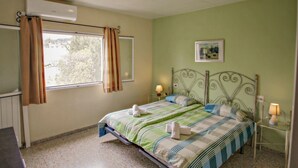A bedroom with a bed, a window with curtains, a bedside table with a lamp, and a wall-mounted air conditioner. - Bal-30E - traditionally furnished detached villa with peaceful surroundings in Benissa (Benissa)