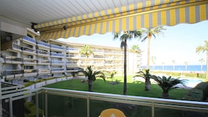 Un balcon d’hôtel avec vue sur une piscine, des palmiers et une plage.