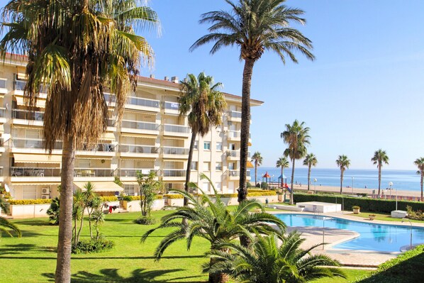 A hotel with a pool, palm trees, and a view of the beach.