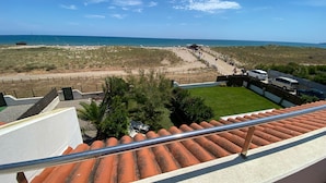 Blick vom Balkon auf einen Strand bei klar blauem Himmel.