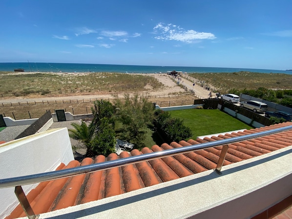 Vista desde un balcón sobre una playa, con cielo despejado.