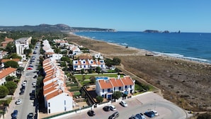 Eine Küstenwohngegend mit einer Häuserreihe, einem Strand und freiem Blick auf das Meer.
