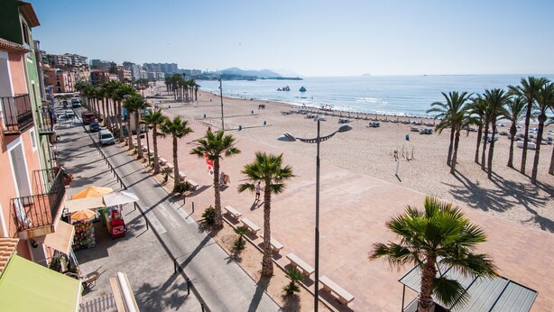 Una strada lungo la spiaggia, con palme, panchine e una vista libera sull'oceano.