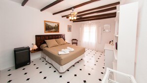 Una camera da letto con un letto, una ventola a soffitto, un comodino, una sedia e un tavolino con una lampada.