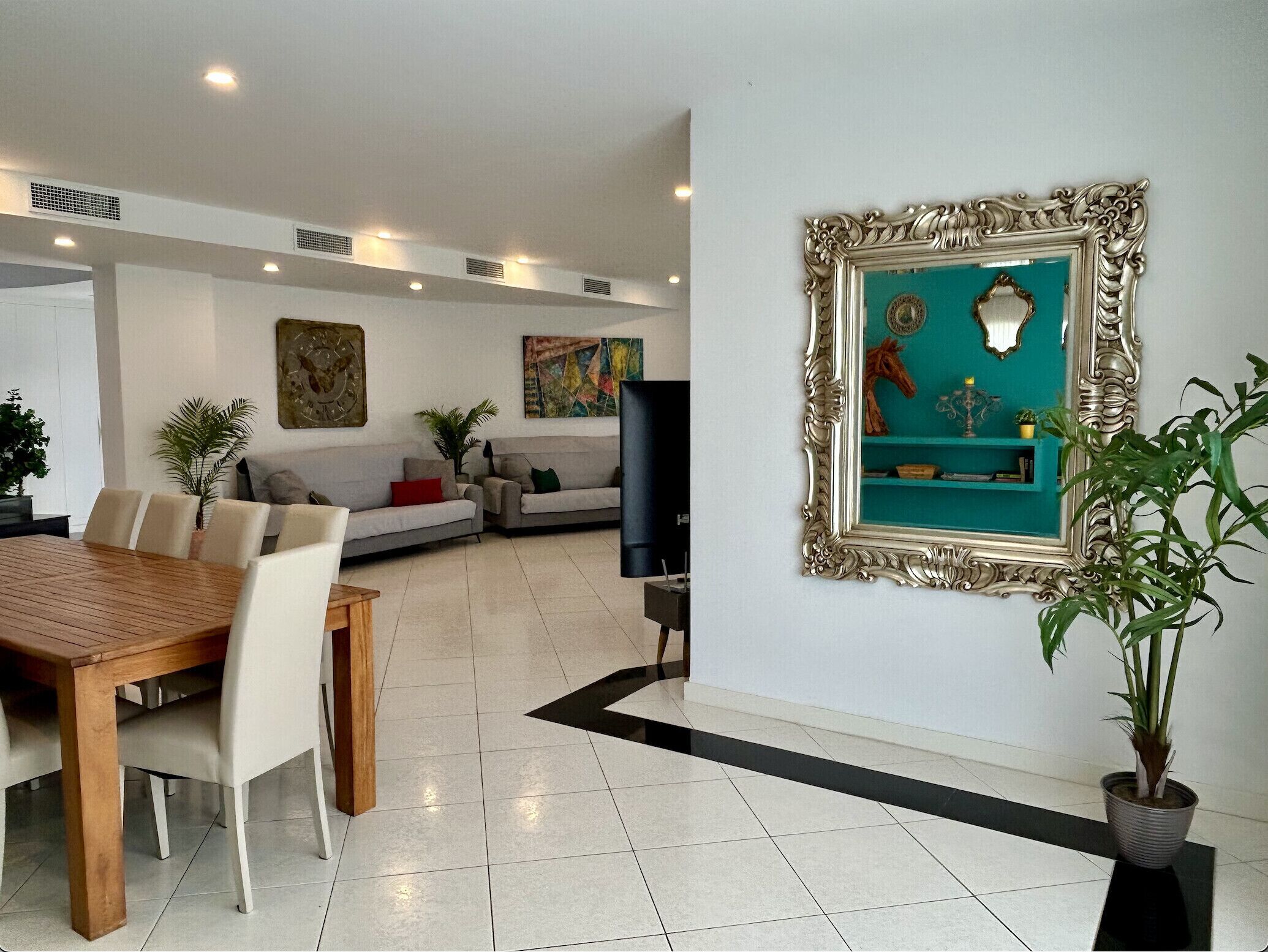 A modern living room with a dining area, a sofa set, and a decorative wall piece.