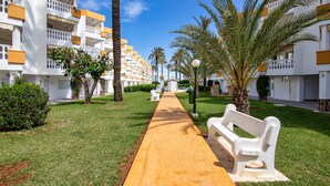 A pathway leading to a building with balconies, surrounded by palm trees and greenery. - Holiday Beach - Denia, Costa Blanca (Denia)