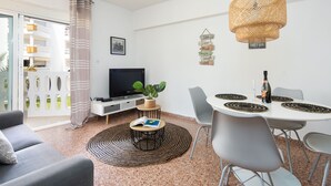 A modern living room with a sofa, TV, dining table with chairs, and a plant on a small table. - Holiday Beach - Denia, Costa Blanca (Denia)