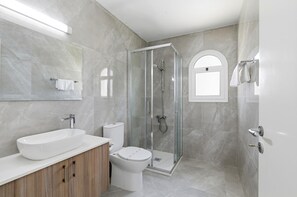 Ein modernes Badezimmer mit einer begehbaren Glasdusche, einem weißen Waschbecken und einer Toilette.