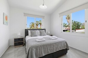 Ein Schlafzimmer mit einem Bett, zwei Nachttischen, einem Fenster und einer Deckenleuchte.