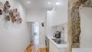Una cocina moderna con armarios blancos, una pared de acento de piedra y piso de madera.