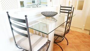 Zona pranzo con tavolo in vetro, due sedie e una ciotola decorativa.