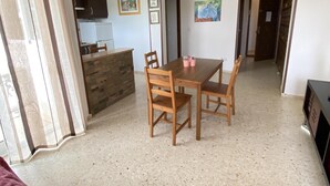 Ein Essbereich mit Holztisch und -stühlen, im Hintergrund eine Küche und ein Deckenventilator.