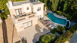 Une maison moderne à deux étages dotée d’une piscine, d’un espace salon extérieur et d’un jardin.