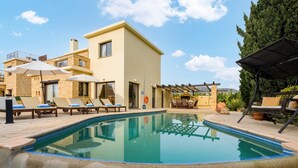 Un espace aménagé au bord de la piscine, avec des chaises longues, des parasols et une pergola.