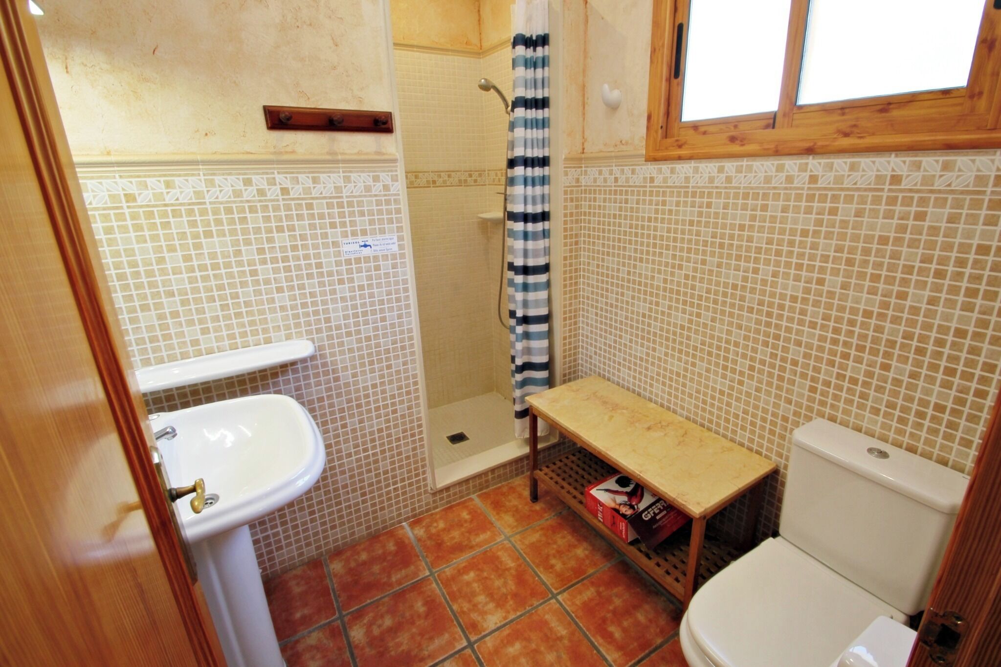 Ein kleines Badezimmer mit Waschbecken, Toilette, Dusche und einem kleinen Tisch.