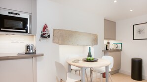 A modern kitchen with a microwave, toaster, and a dining table with chairs. - The Design Studio (Bath)