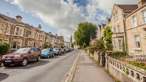 A street lined with terraced houses, parked cars, and a clear sky. - The Design Studio (Bath)