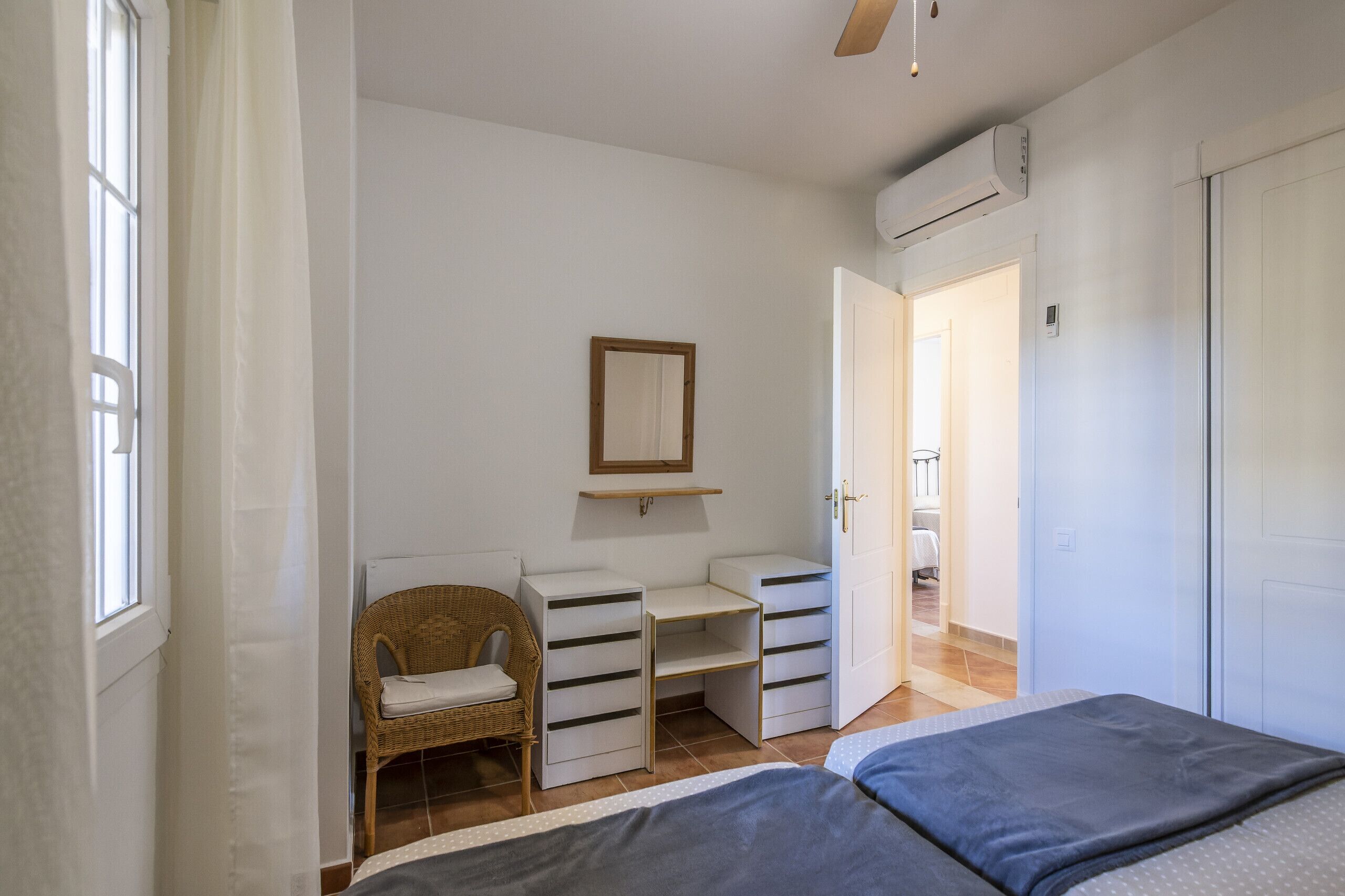 Un dormitorio con cama, una silla, armario, espejo y estante.