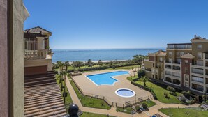 Un resort con una piscina grande, vistas al mar y un jardín bien cuidado.