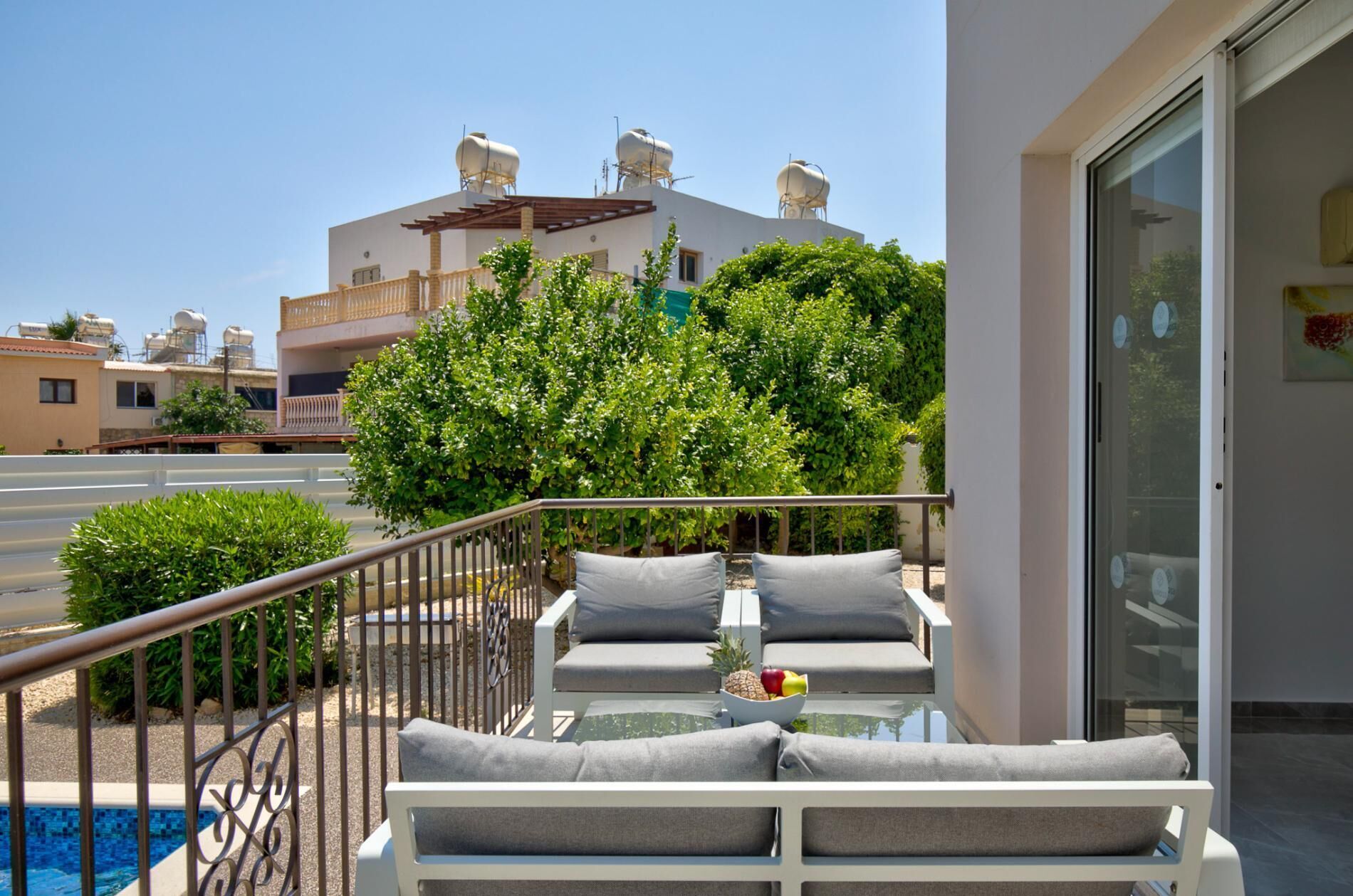 A balcony with a pool, outdoor seating, and a view of a building with water tanks.
