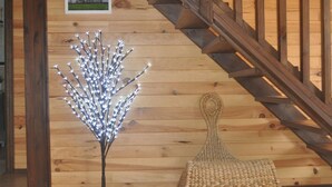 Una escalera de madera con un banco tejido y una escultura de árbol decorativa.