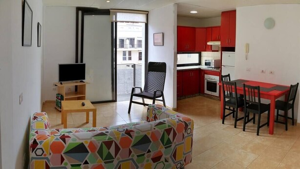 Un salon comprenant un canapé, un téléviseur et un coin repas avec des chaises et une table.
