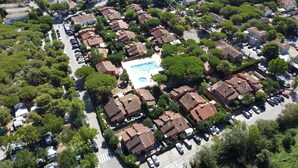 Vista aérea de una zona residencial con casas escalonadas, una piscina central y abundante vegetación.