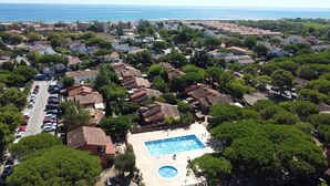 Vista aérea de una zona residencial costera con piscina, casas y coches aparcados.