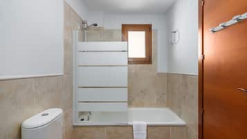 A bathroom with a shower, toilet, and a wooden door.