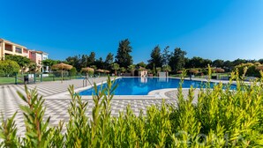 Una piscina con borde de baldosas, rodeada de follaje y árboles.