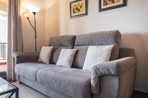 A grey sofa with multiple cushions, a floor lamp, and two framed artworks on the wall. - El Rincon del Golf III PLUS - Isla Canela Golf GRHIII88P88 (Isla Canela)