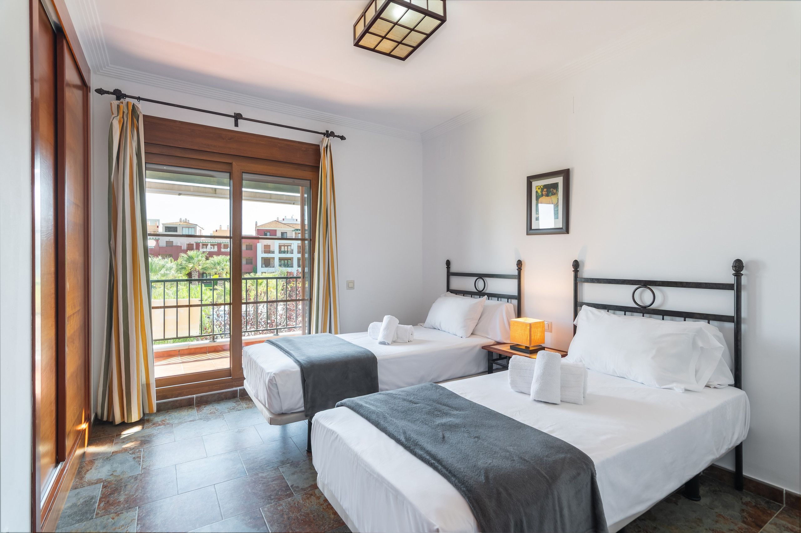 Habitación de hotel con dos camas, un balcón y vistas a edificios.