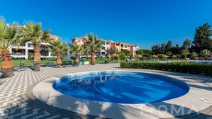 Una piscina rodeada de palmeras y un edificio con balcones.