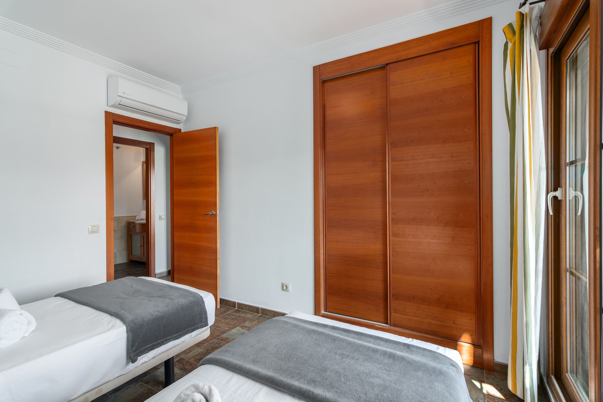 Una camera d'albergo con due letti, un armadio e un condizionatore.