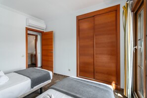 A hotel room with two beds, a wardrobe, and an air conditioning unit. - El Rincon del Golf III PLUS - Isla Canela Golf GRHIII88P88 (Isla Canela)