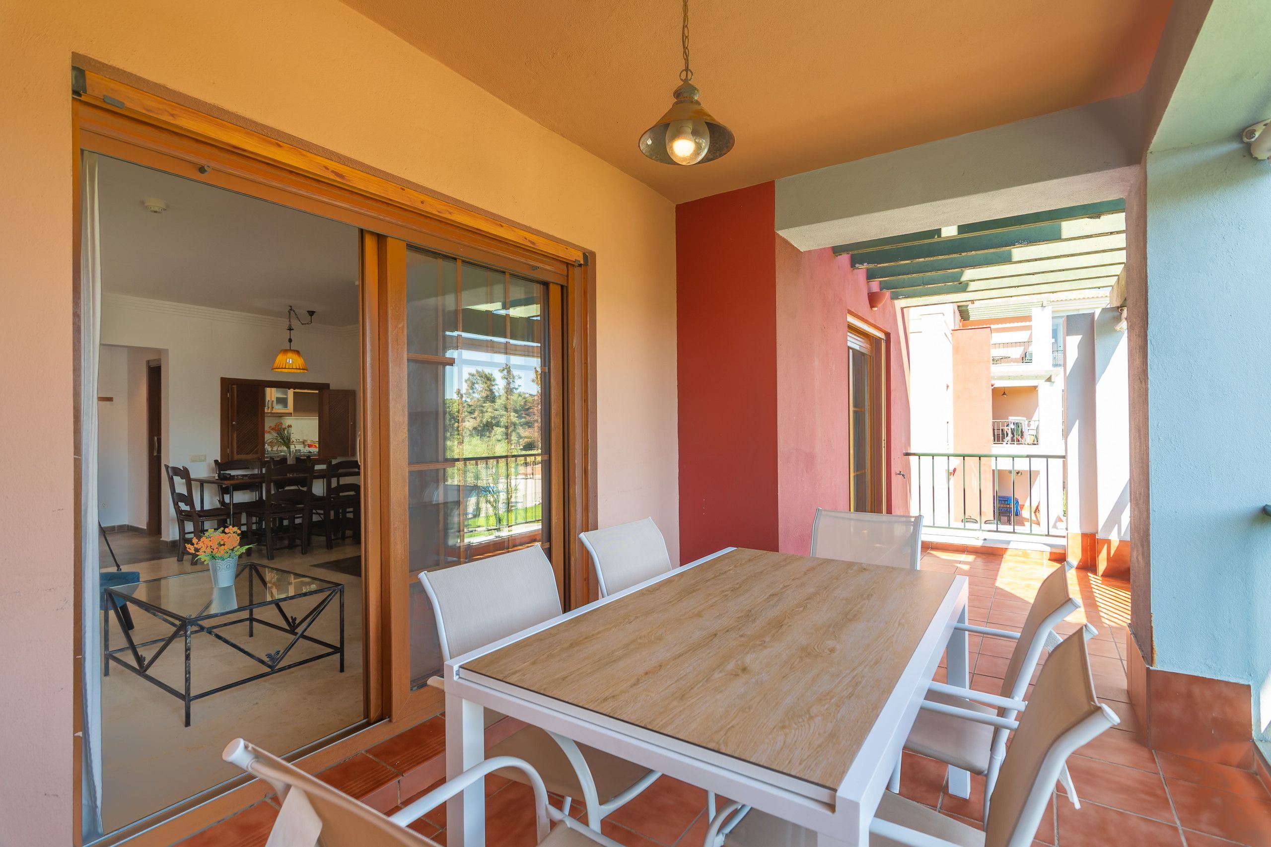 Zona pranzo con tavolo e sedie, una parete divisoria in vetro e vista sull'interno.