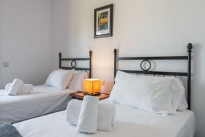 A hotel room with two single beds, each with white linens and pillows, a bedside table with a lamp, and a framed picture on the wall. - El Rincon del Golf III PLUS - Isla Canela Golf GRHIII88P88 (Isla Canela)