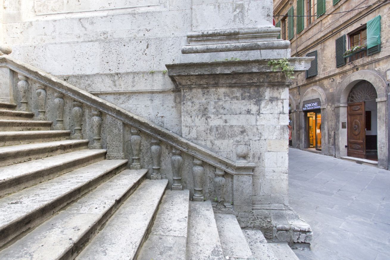 Eine steile Steintreppe führt zu einem Gebäudeeingang, an dem ein Schild mit dem Schriftzug "SIMONE" befestigt ist.