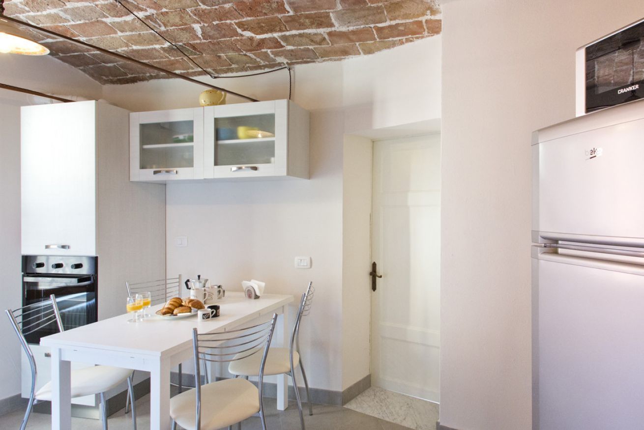Une cuisine moderne avec des meubles blancs, un four encastré et un réfrigérateur.