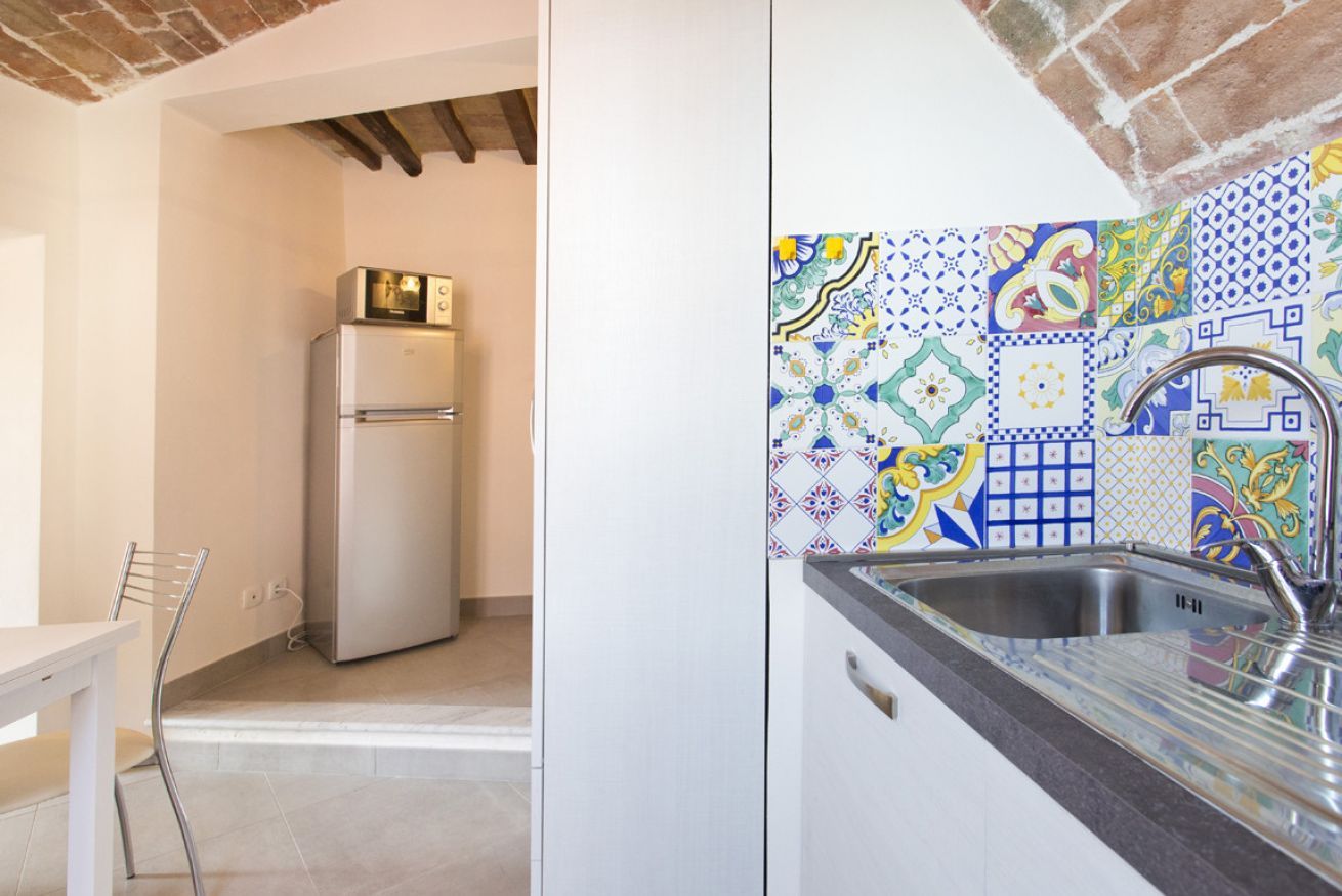 A kitchen with a refrigerator, a sink, and a chair.