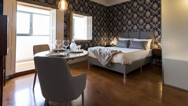A bedroom with a bed, bedside table, and a dining area with a table and chairs. - The Brewmaster's House 4 | Studio Deluxe (Porto)