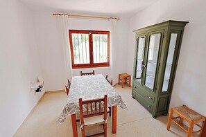 A dining area with a table, chairs, a cabinet, and a window.