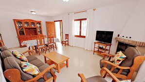 A living room with a sofa set, wooden coffee table, TV, fireplace, and a dining area with chairs and a cabinet. - Laura-29A - pretty holiday property with garden and private pool in Calpe (Calpe)