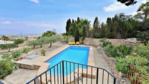 A swimming pool with a stone border, surrounded by greenery and a view of a cityscape. - Laura-29A - pretty holiday property with garden and private pool in Calpe (Calpe)